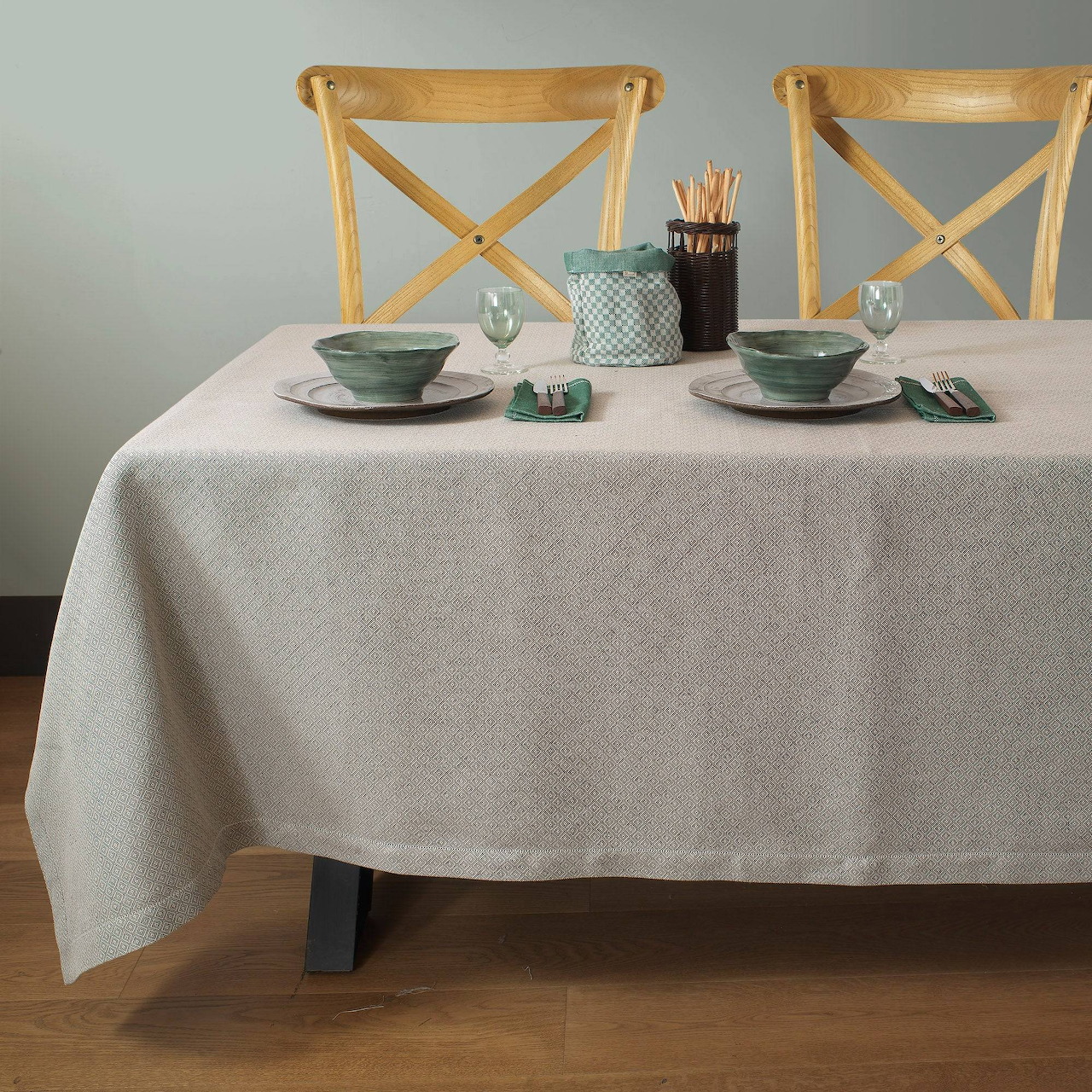 Dining table with white tablecloth, two wooden chairs, bowls, cups, and cutlery