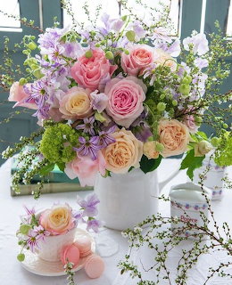 Mixed rose bouquet with pink, peach and lavender roses in white ceramic vase with smaller arrangement in teacup