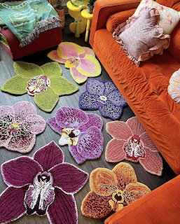 Several orchid-shaped decorative rugs in various colors spread on floor beside an orange couch