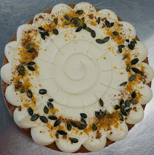 Top view of a frosted pumpkin spice cake topped with pumpkin seeds and spice crumbs