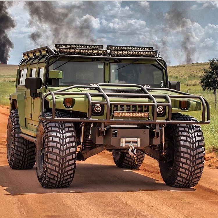 Armored off-road vehicle parked on a dirt road beneath a cloudy sky