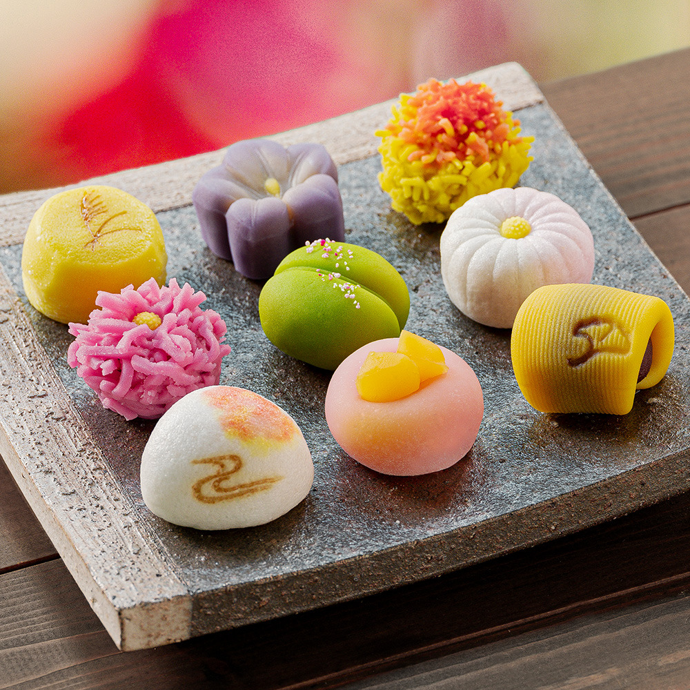 Assortment of nine colorful Japanese wagashi sweets displayed on a wooden board