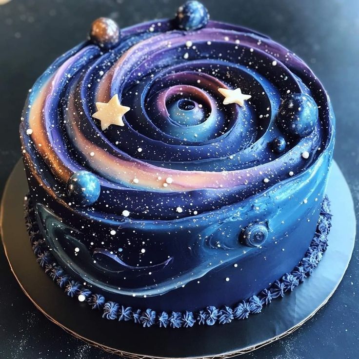Round cake decorated with spiral galaxy design in blue, purple, and pink with edible stars and planets
