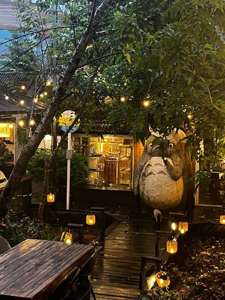 Outdoor café in Da Lat Vietnam with string lights, lanterns, wooden deck, and large Totoro statue among trees