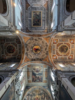 Ornate frescoed ceiling and dome of Basilica di Santa Maria in Vado with painted panels and gilded arches
