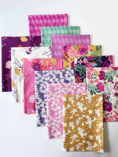 Stack of colorful patterned fabric squares for quilting in various floral and geometric designs