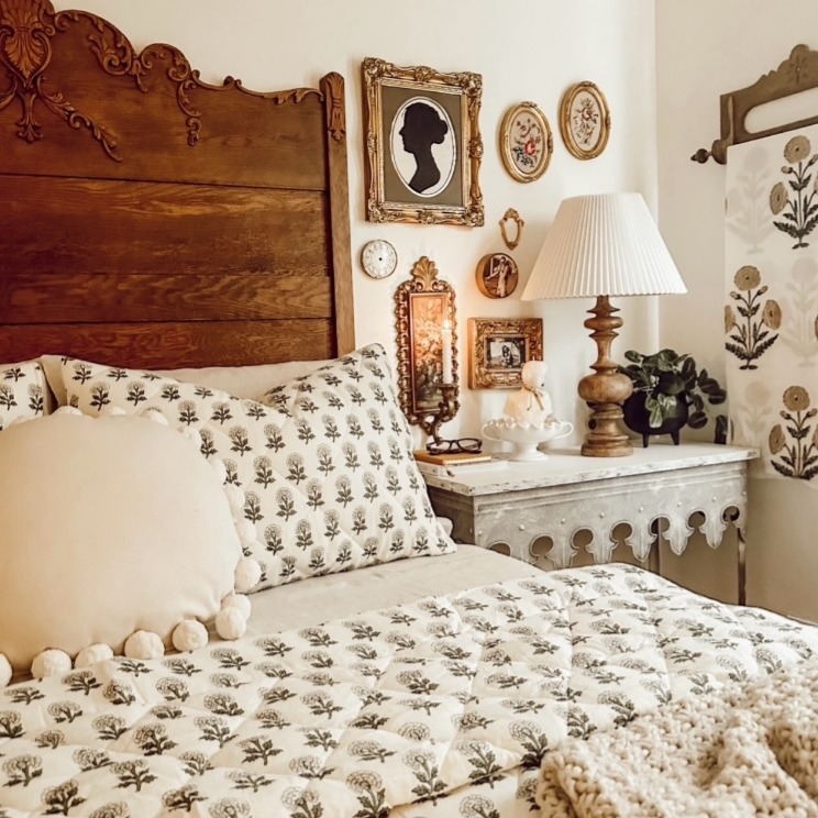 Cozy vintage bedroom with patterned bedding, wooden headboard, lamp, and framed wall decor