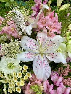 Close-up of a flower bouquet with white speckled lilies, pink snapdragons, and assorted white bloms