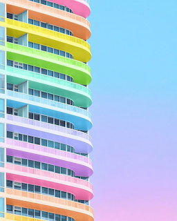 Curved high-rise building with stacked rainbow-colored balconies in pastel hues against pink and blue gradient sky