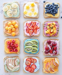 Twelve pieces of toast arranged in a grid, each topped with different fresh fruits and cream cheese