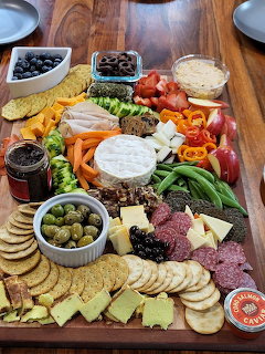 Halloween-themed charcuterie board with cheese shapes, crackers, meats, fruit, olives, and vegetables