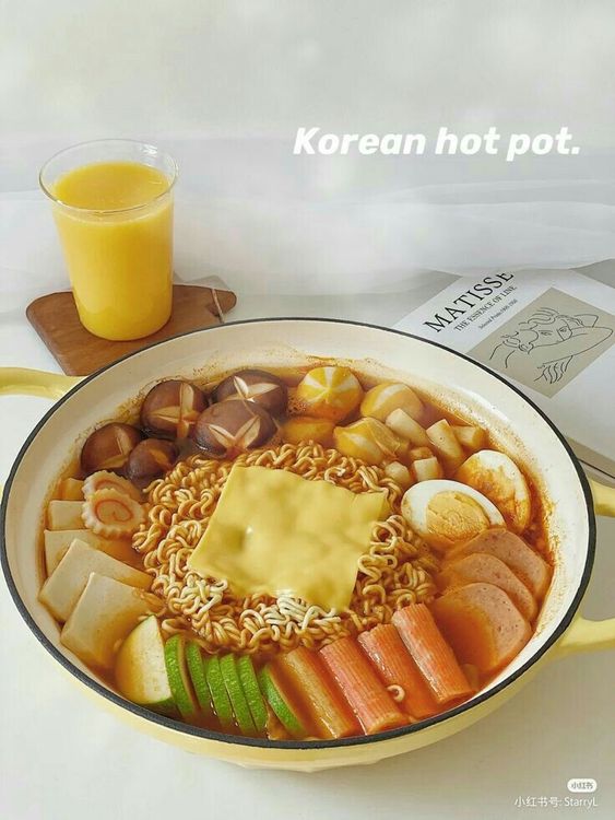 Korean hot pot with ramen noodles, spam, eggs, fish cakes, and melted cheese in a yellow pot