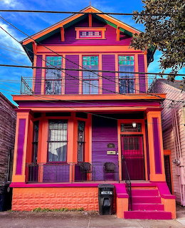 Bright purple and orange painted Victorian-style house with front porch and steps
