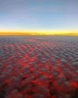 Sunrise over a wide layer of clouds with red and golden light on the cloud tops