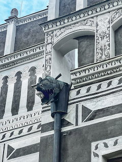 Dragon figure on a street lamp against an ornate sgraffito Renaissance building façade in Český Krumlov