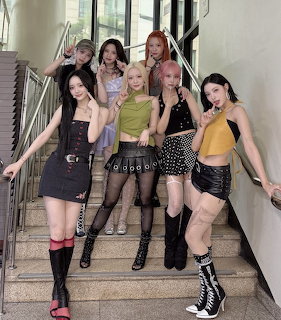 Seven young women in trendy outfits posing on stairs in modern building