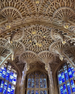 Ornate fan vaulted stone ceiling of Westminster Abbey Lady Chapel with blue stained glass windows