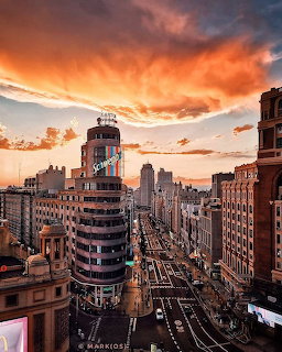 Aerial view of Madrid city street at sunset with dramatic orange clouds and historic buildings