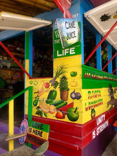 Colorful tropical juice stand with painted fruit mural and cane juice sign