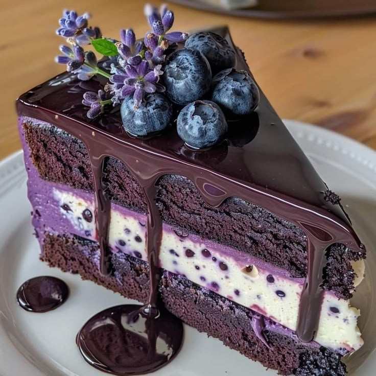 Slice of chocolate layered cake with blueberries and cream filling, topped with fresh berries and flowers