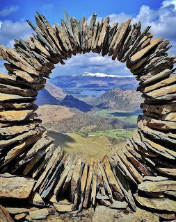 Circular driftwood frame surrounding mountain valley landscape view under blue sky