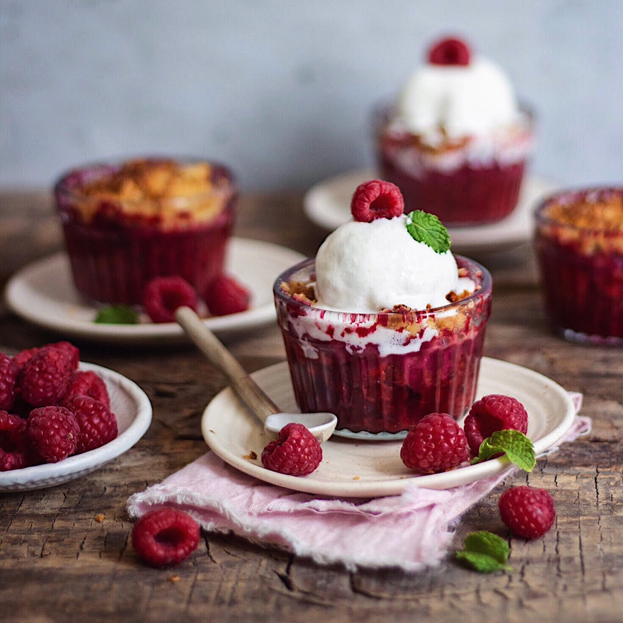 Raspberry dessert cups with whipped cream and fresh raspberries on white plates
