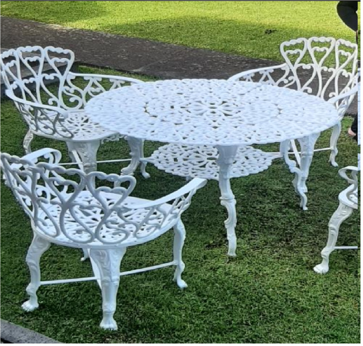 White ornate metal outdoor table and chairs on grass
