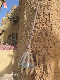 Traditional dutar string instrument hanging on a rustic adobe mud wall in Xinjiang, China
