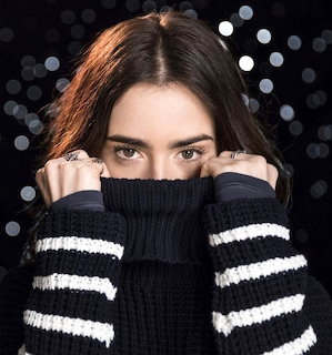 Woman with dark hair covering lower face with black and white striped turtleneck sweater