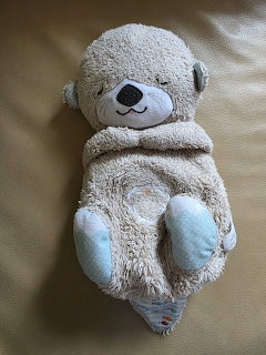 Soft plush teddy bear lying on a beige surface with pale blue feet