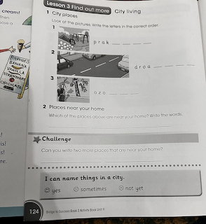 English activity book page with city places vocabulary exercises, small city illustrations, and writing prompts for children.