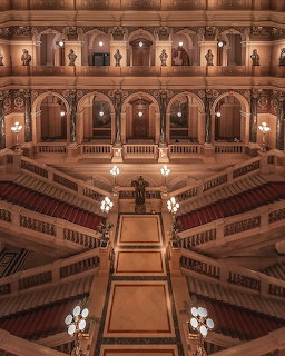 Grand interior staircase of the National Museum in Prague with arched galleries and ornate chandeliers