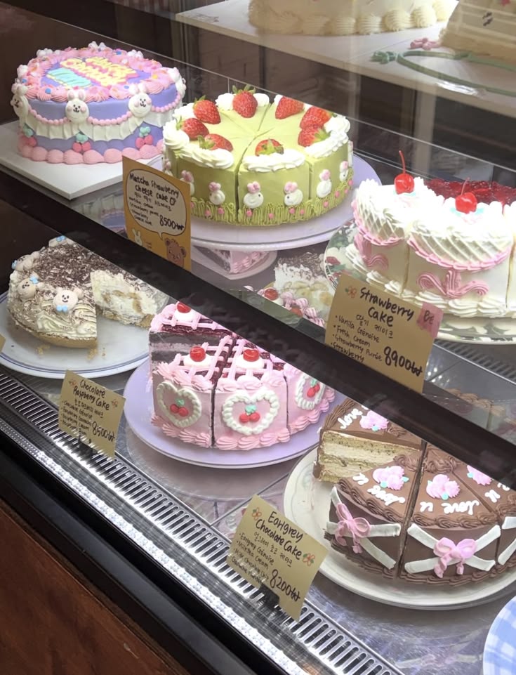 Decorated cakes and cake slices displayed inside a bakery glass case