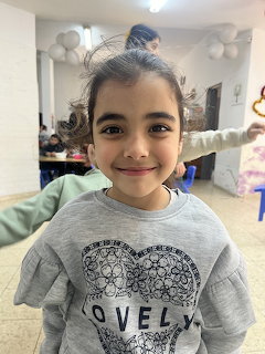 Young smiling girl with hair bun wearing gray Lovely sweatshirt at an indoor party with balloons