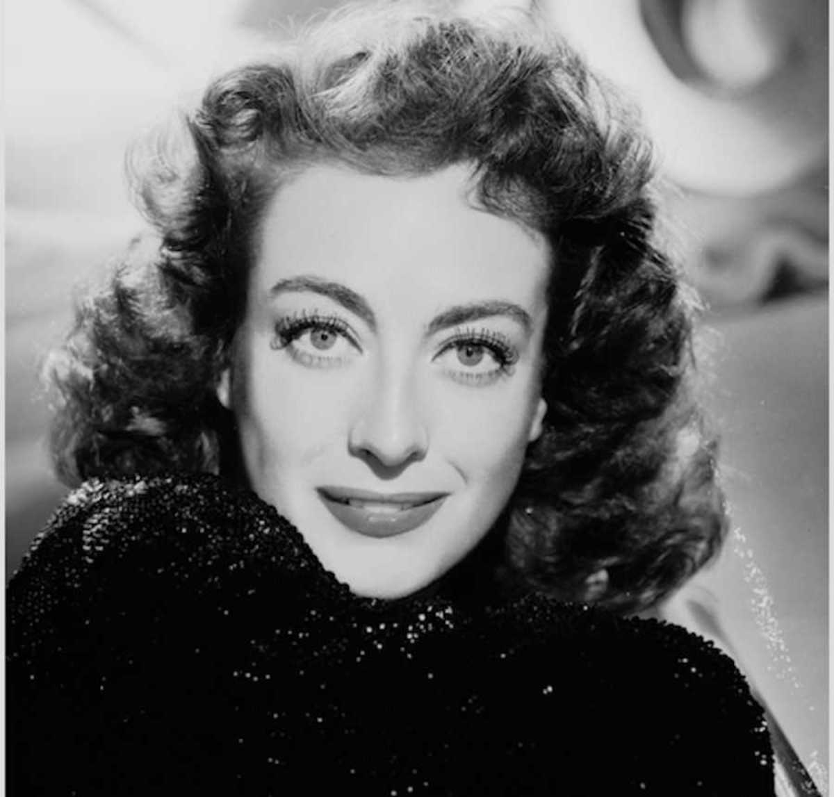 Black and white portrait of Joan Crawford with curled hair and sparkling dress, classic Hollywood style