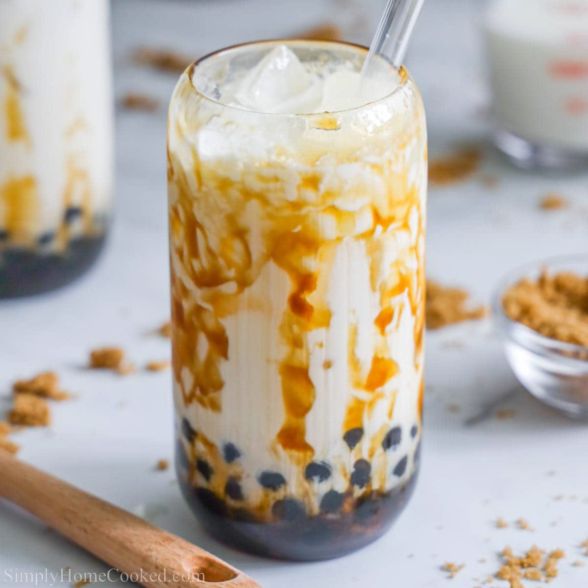 Tall glass of brown sugar boba milk tea with tapioca pearls, caramel syrup, and ice