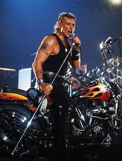 Johnny Hallyday performing on stage beside a custom motorcycle