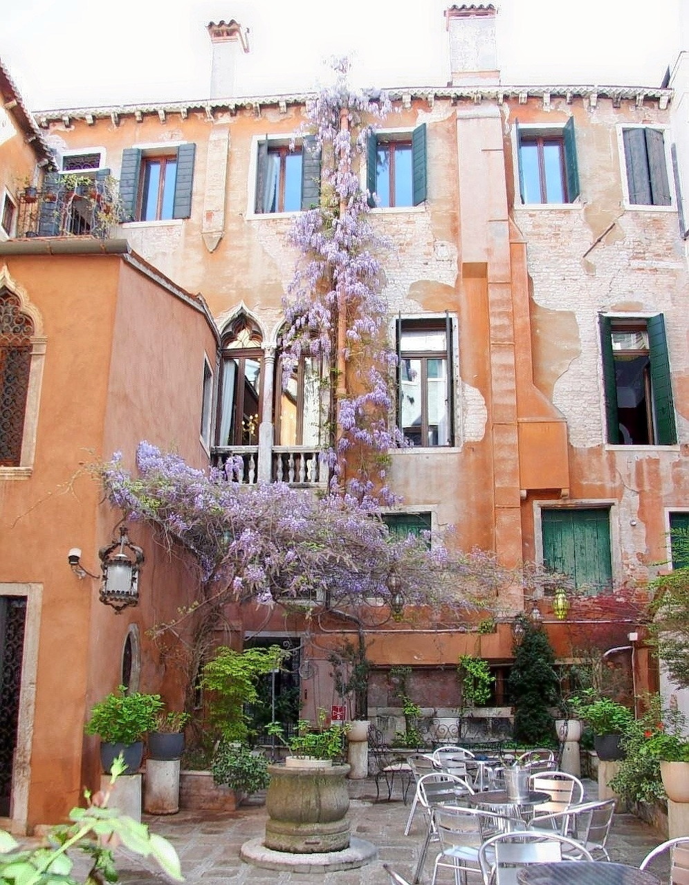Venetian courtyard with bloming wisteria climbing between old buildings and outdoor café seating