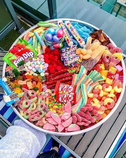 Round white tray filled with assorted colorful candies, gummies, chocolates, and sweets