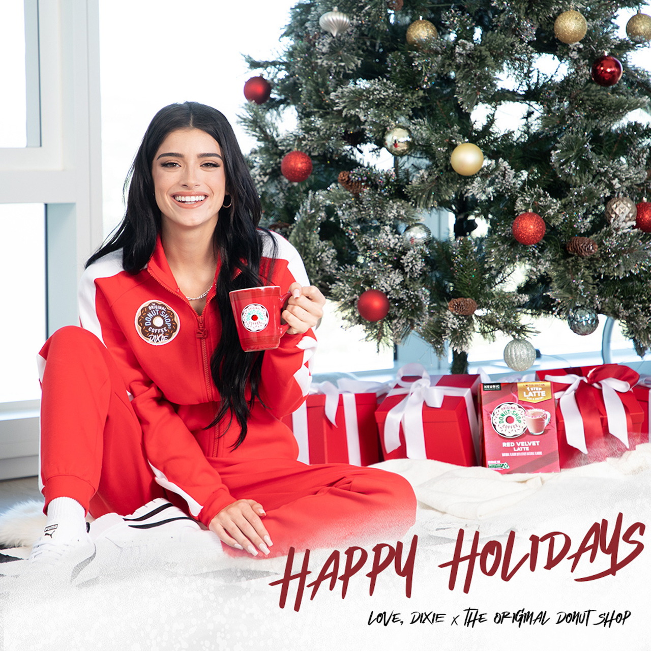 Woman in red holiday sweater smiling beside decorated Christmas tree with gifts