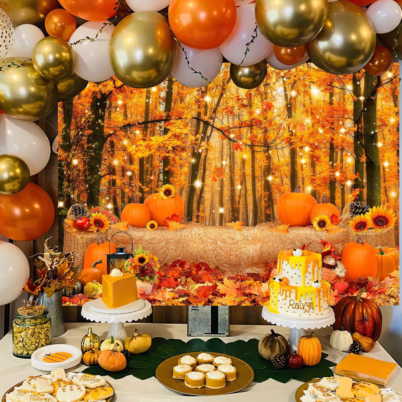 Autumn themed dessert table with cakes, pumpkins, balloons and forest background