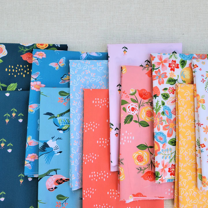 Row of folded fabric samples with floral and geometric patterns in blue, pink, coral, and yellow colors