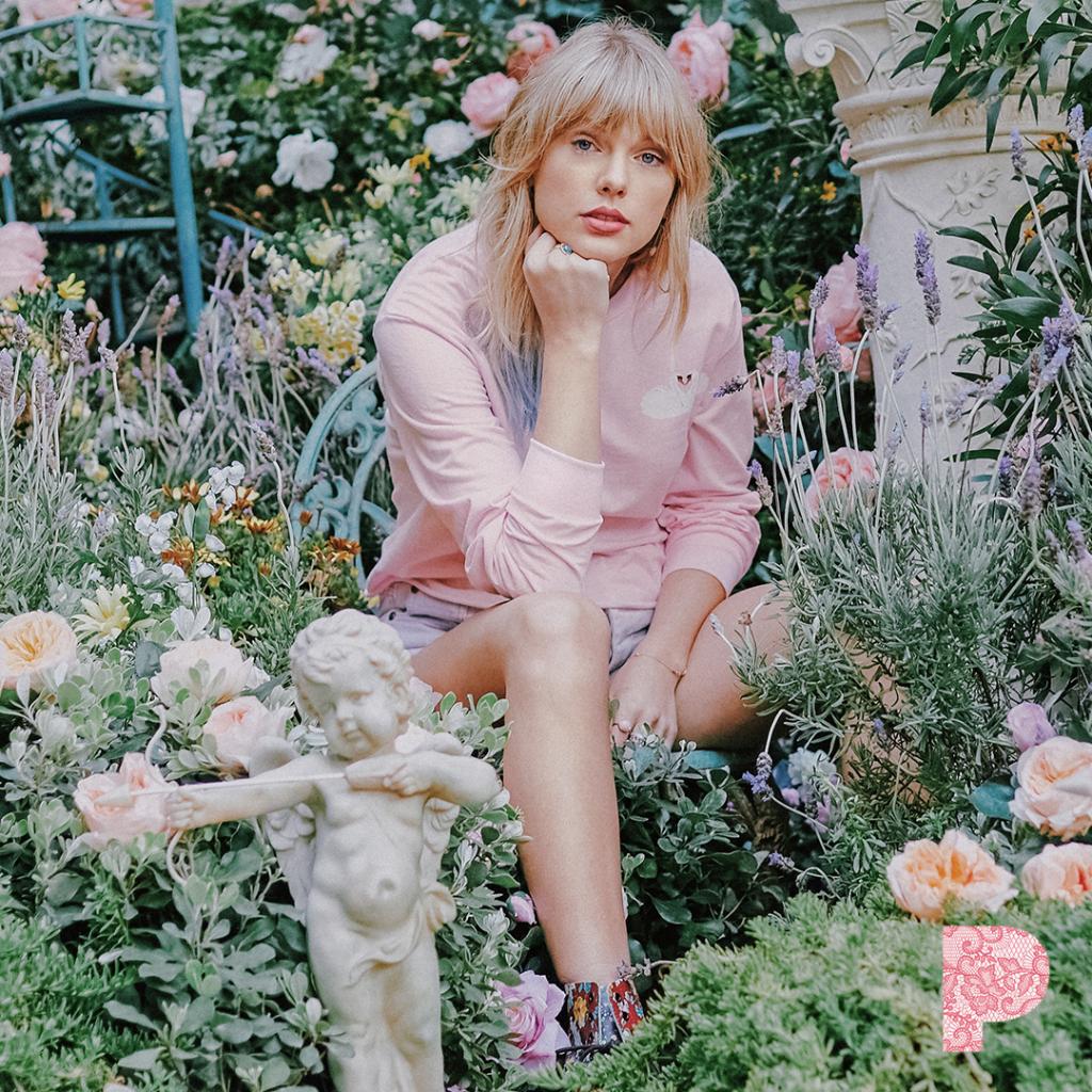 Woman with blonde hair sitting in a garden surrounded by flowers and plants