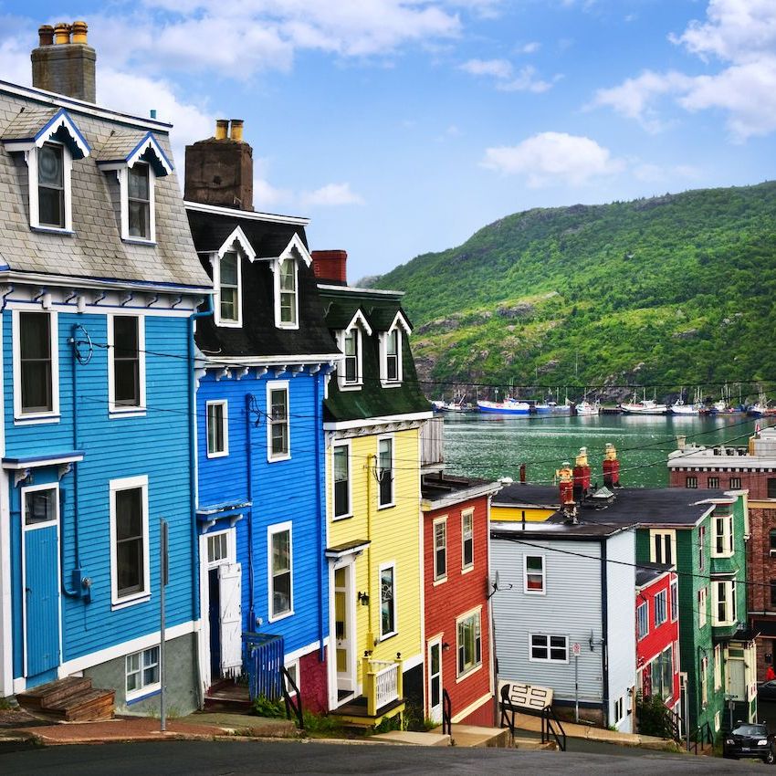 Colorful row houses on a hill in St. John's, Newfoundland with harbor and green hillside behind