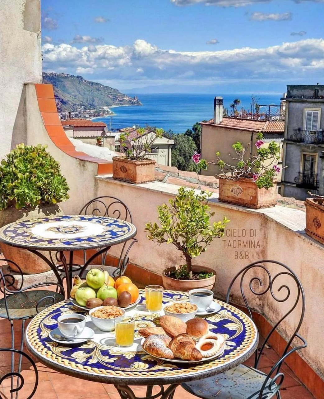 Terrace breakfast table with sea view and Sicilian coastal town in background