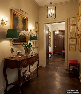Elegant hallway with antique console table, gold-framed art, lantern pendant light, and dark herringbone wood floor