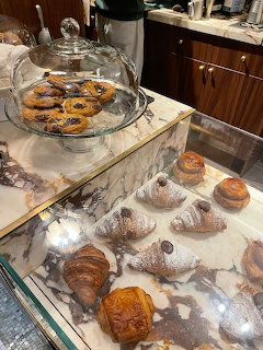 Marble café counter with assorted pastries, croissants, and cookies under a glass cloche