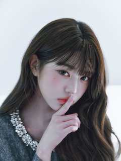 Young woman with brown hair and bangs posing with finger on her lip in a close-up portrait
