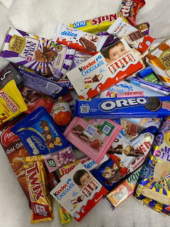 Pile of assorted chocolate bars and candy packages including Oreo, Kinder, Twix on white background