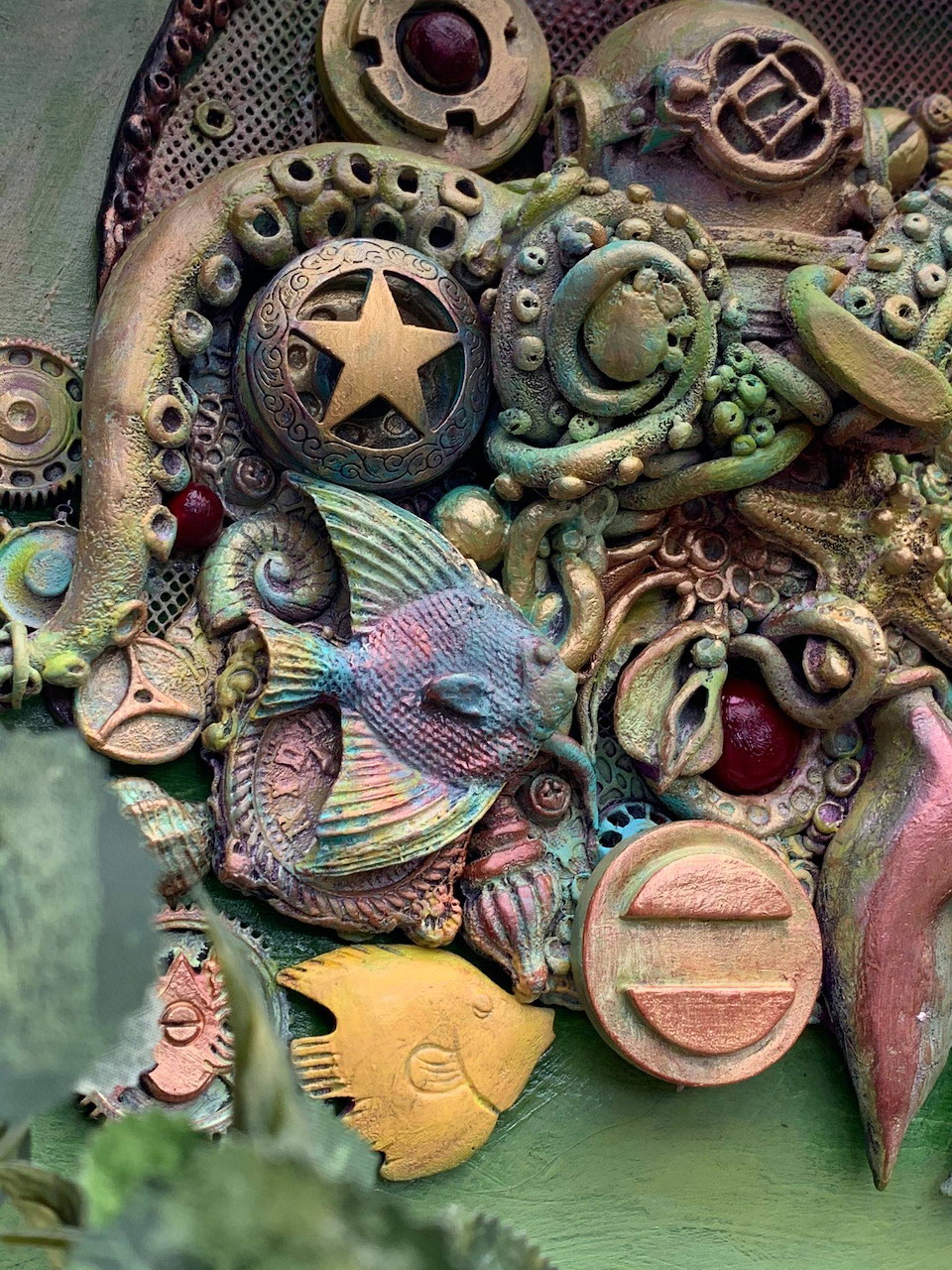 Sculptural relief with colorful fish, gears, octopus tentacles, and a star emblem in green and terracotta